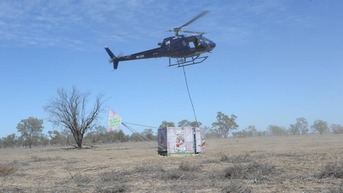 The loaded Grass Storm seeder lifts off with the helicopter. The tail on the seed box keeps it straight in flight.
