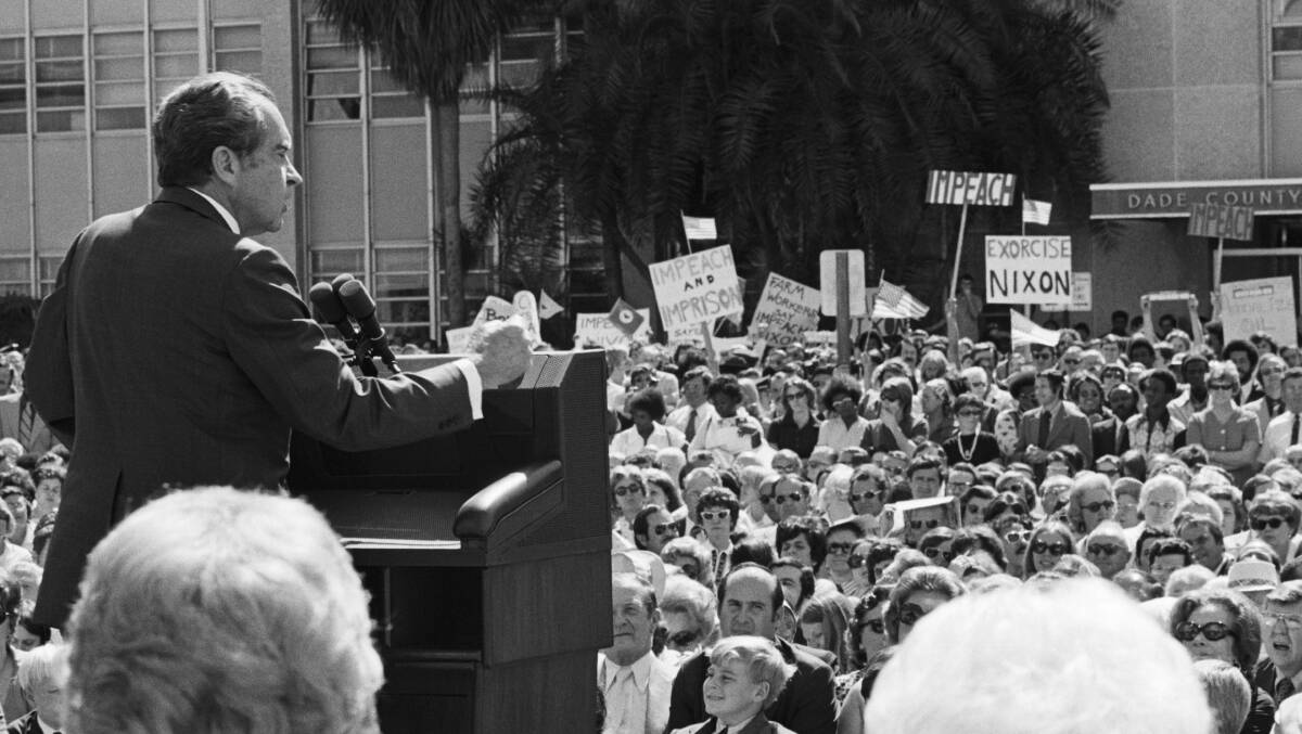 US president Richard Nixon addresses a crowd in 1974. In the background are protesters carrying signs in support of his impeachment. Picture: Getty Images