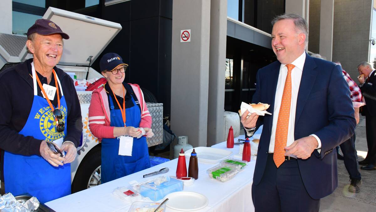 ALBO GREASE: Dubbo West Rotary members Paul Allan and Genevieve Menzies serve Anthony Albanese at the sausage sizzle. Photo: BELINDA SOOLE

